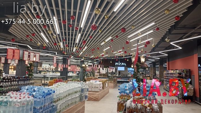 Украшение потолка подвешенными новогодними шарами красного цвета.