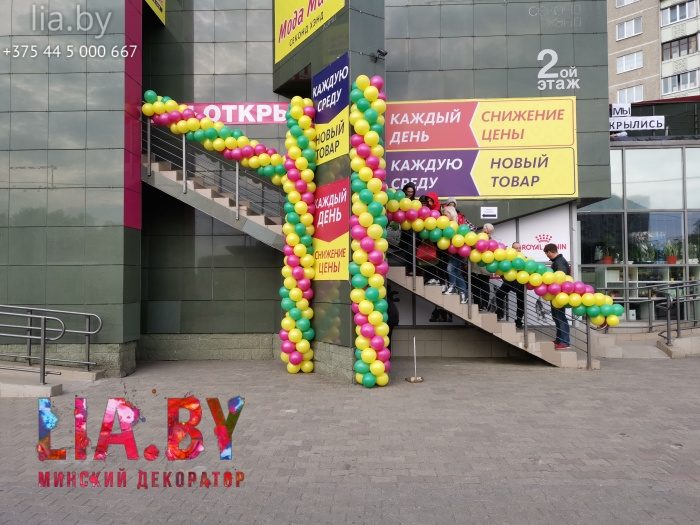 Пышное украшение гирляндой из шаров желтого, розового и зеленого цвета магазина одежды на его открытие