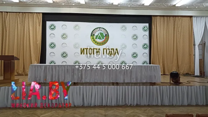 Украшение сцены для подведения итогов белой тканью и вазонами.