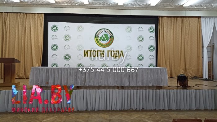 Украшение сцены для подведения итогов белой тканью и вазонами.